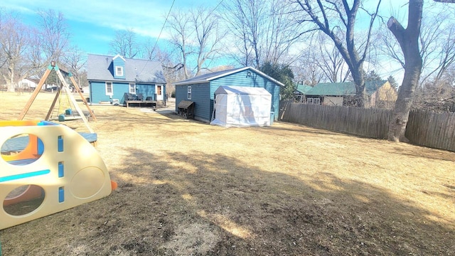 view of yard with an outbuilding, a storage unit, fence, and a detached garage