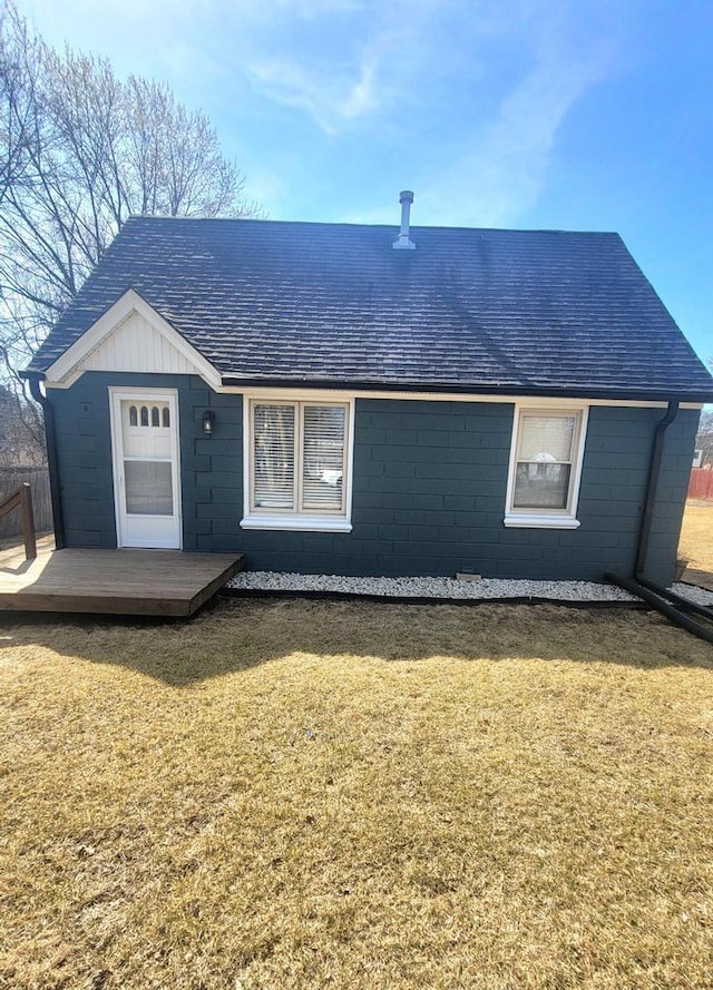 view of front of home featuring a deck, a front yard, and roof with shingles