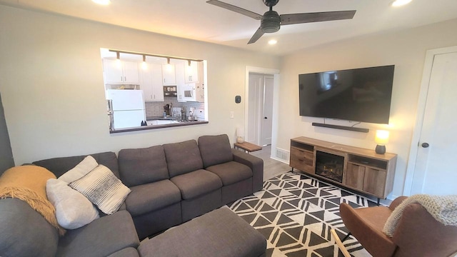 living area featuring visible vents, a glass covered fireplace, recessed lighting, baseboards, and ceiling fan