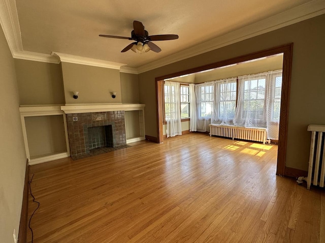 unfurnished living room featuring a fireplace, radiator, wood finished floors, and ornamental molding