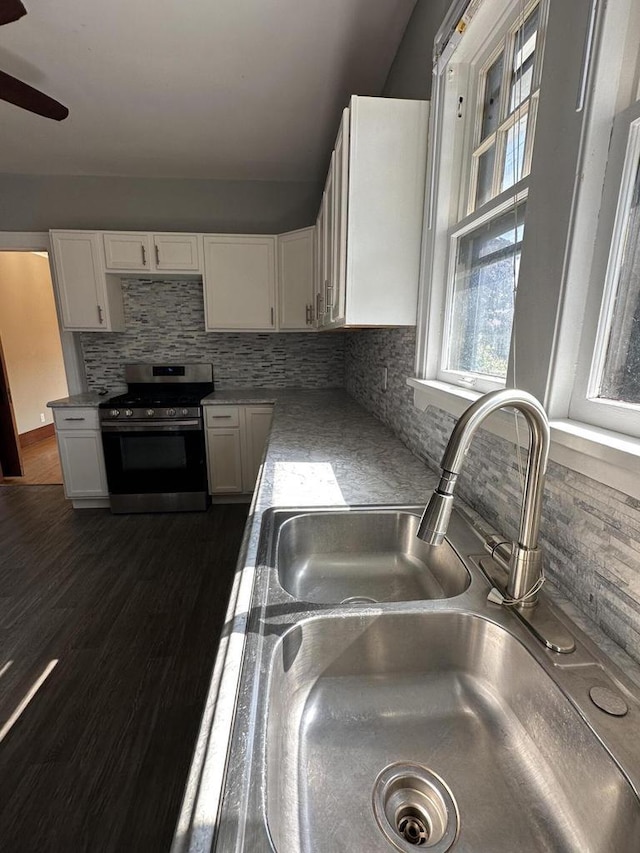 kitchen featuring decorative backsplash, white cabinetry, stainless steel gas range, and a sink