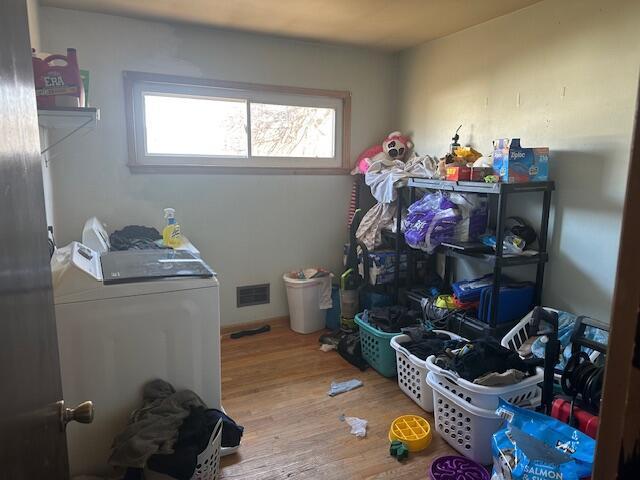 laundry area featuring washing machine and clothes dryer, laundry area, visible vents, and wood finished floors