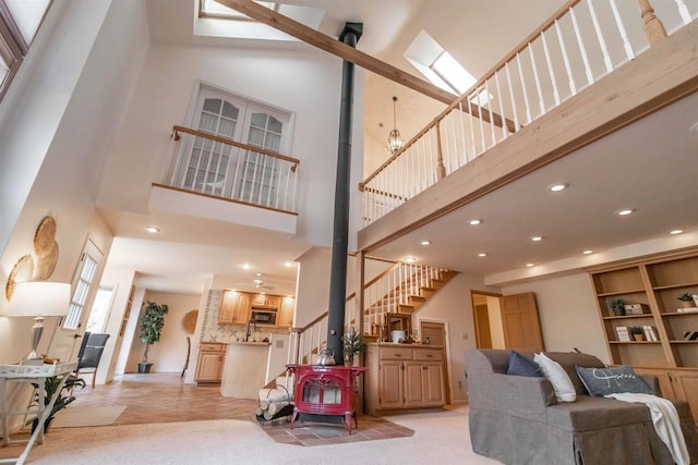 living area with a wood stove, light carpet, recessed lighting, a towering ceiling, and stairs