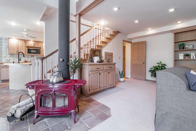 living area with light colored carpet, stairs, recessed lighting, a wood stove, and a ceiling fan