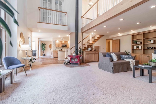 living area with a wood stove, recessed lighting, carpet, and a high ceiling