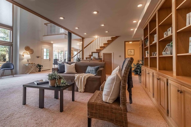 living area with stairs, recessed lighting, and light carpet