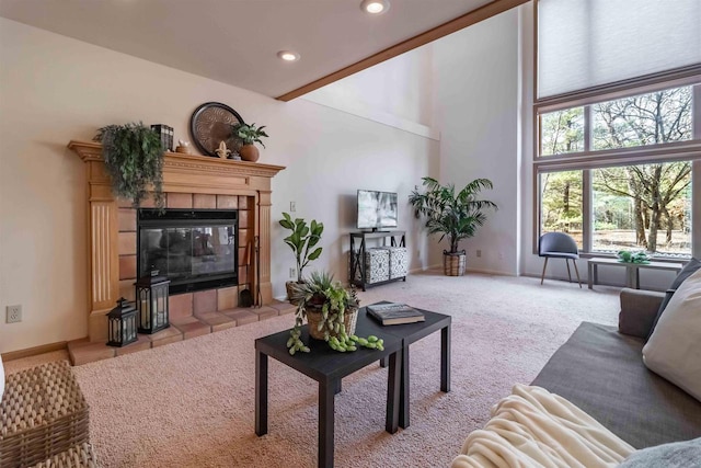 living area with baseboards, carpet floors, a fireplace, recessed lighting, and a towering ceiling