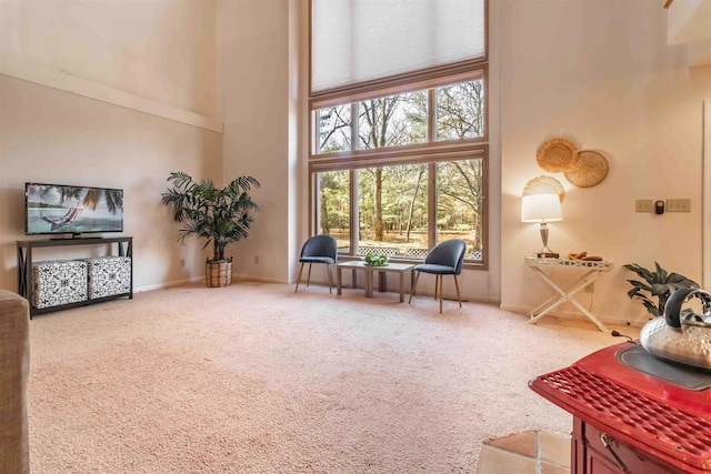 sitting room with baseboards, a towering ceiling, and carpet flooring