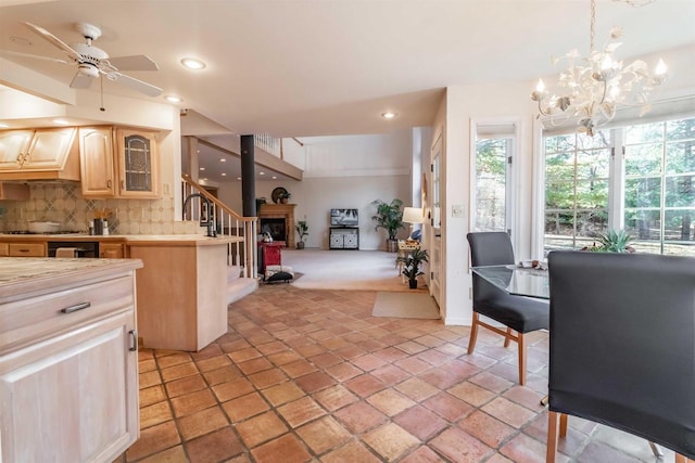 kitchen with light brown cabinets, a fireplace, light countertops, glass insert cabinets, and tasteful backsplash