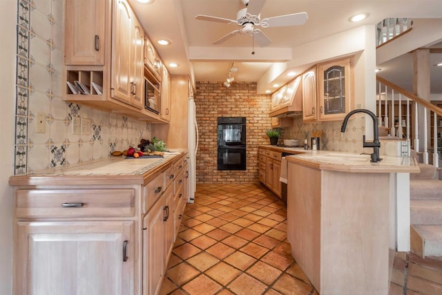 kitchen featuring custom exhaust hood, a sink, decorative backsplash, glass insert cabinets, and dobule oven black