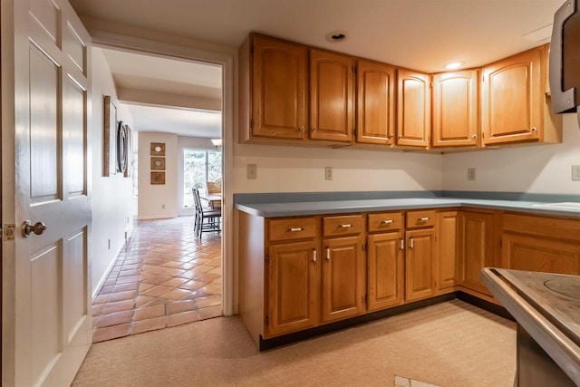 kitchen featuring recessed lighting, baseboards, brown cabinetry, and a sink