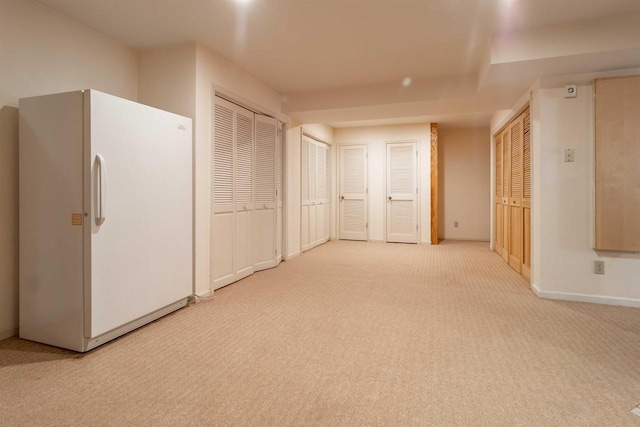 interior space with carpet flooring, two closets, freestanding refrigerator, and baseboards