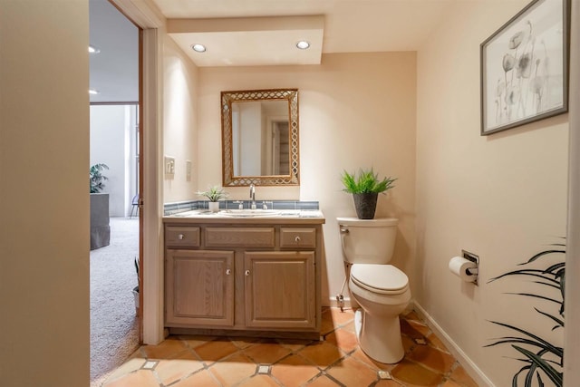 half bathroom featuring vanity, toilet, baseboards, and tile patterned flooring