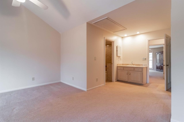 interior space featuring light colored carpet, attic access, baseboards, and a sink