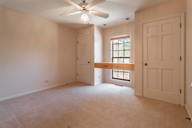 unfurnished room featuring a ceiling fan, carpet, visible vents, and baseboards