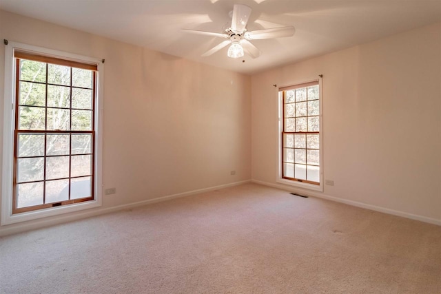 carpeted spare room with a ceiling fan, visible vents, and baseboards