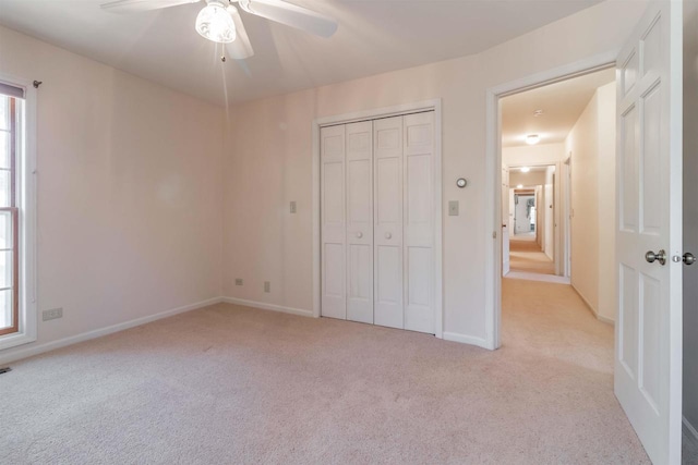 unfurnished bedroom featuring light carpet, multiple windows, baseboards, and a closet