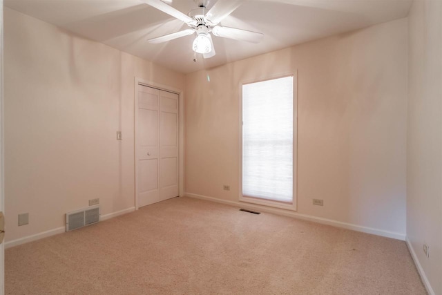 unfurnished room with visible vents, light carpet, baseboards, and ceiling fan