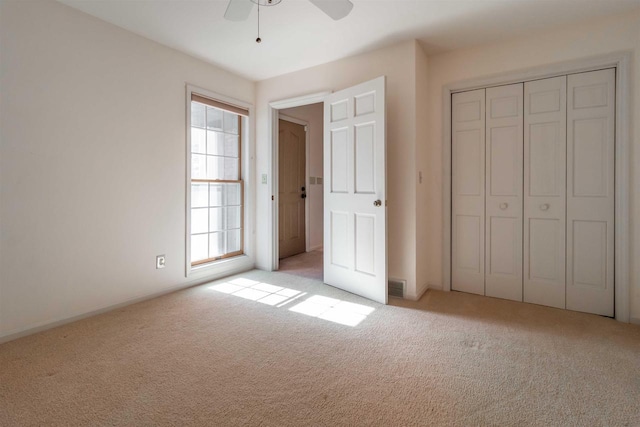 unfurnished bedroom featuring a ceiling fan, visible vents, a closet, and light carpet