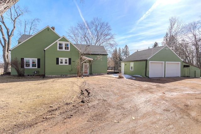 exterior space with a detached garage, an outbuilding, roof with shingles, and a chimney