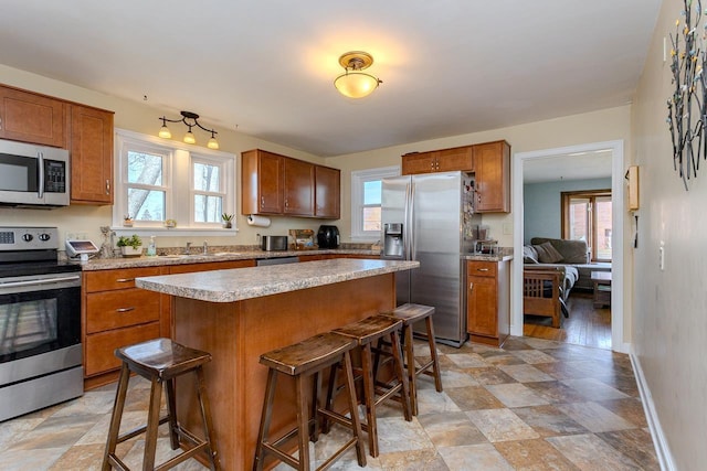 kitchen featuring a wealth of natural light, appliances with stainless steel finishes, a breakfast bar area, and light countertops