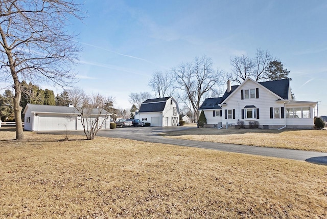 exterior space with an outdoor structure, a garage, a front yard, and a chimney