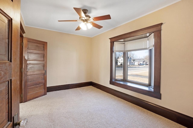 empty room with carpet flooring, ceiling fan, baseboards, and ornamental molding