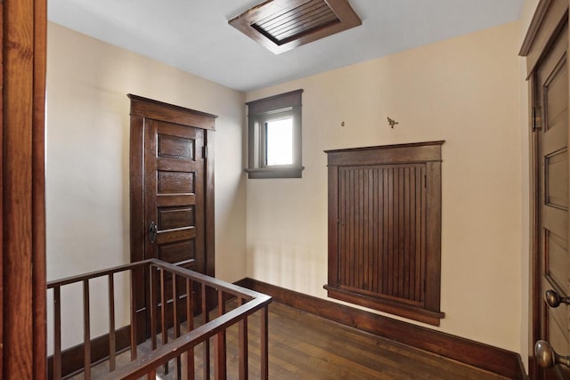 corridor featuring an upstairs landing, wood finished floors, and baseboards