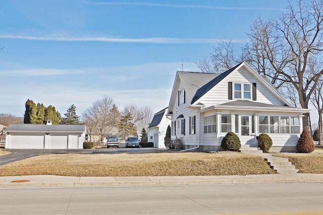 view of front of home with a detached garage and a sunroom