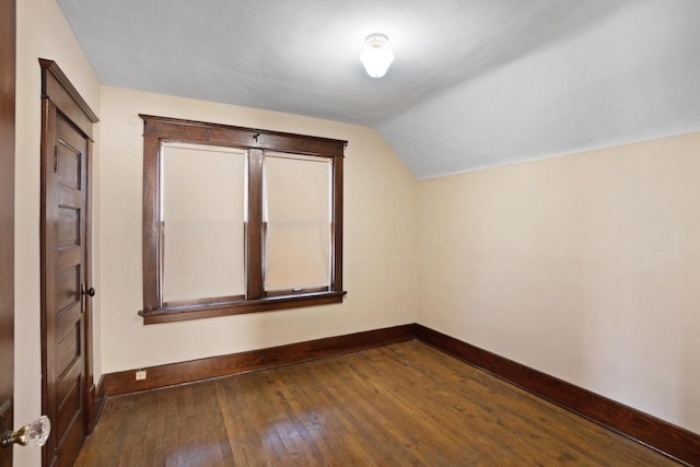 additional living space with dark wood-type flooring, baseboards, and lofted ceiling