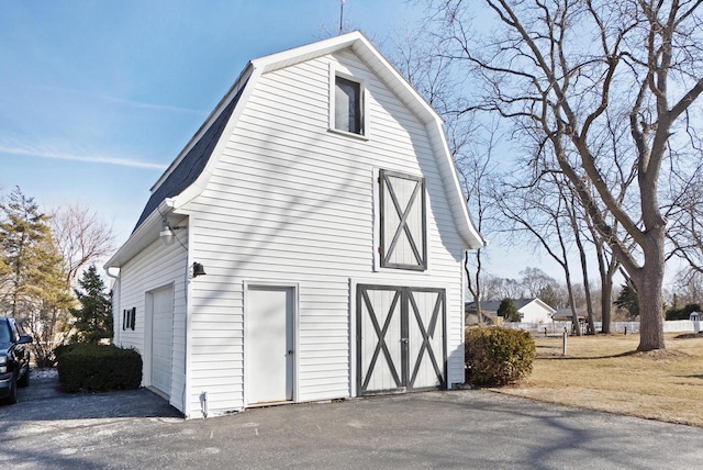 view of side of home featuring a gambrel roof, a barn, and an outdoor structure