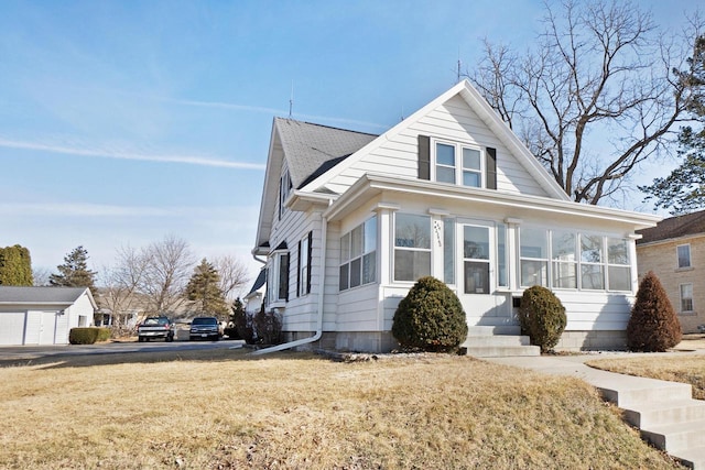 bungalow-style house with roof with shingles, a front lawn, and a sunroom