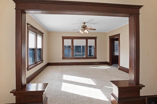 unfurnished room with a ceiling fan, baseboards, and light carpet