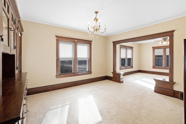 carpeted empty room featuring a notable chandelier and baseboards