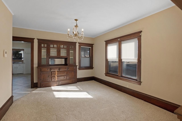 carpeted spare room with tile patterned flooring, a notable chandelier, and baseboards