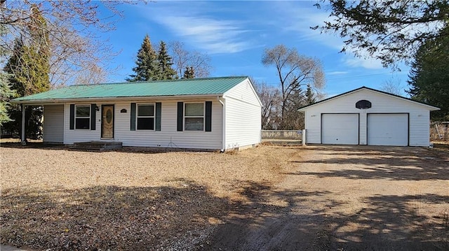 ranch-style house featuring a detached garage, fence, covered porch, metal roof, and an outdoor structure