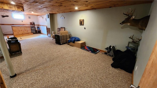 below grade area featuring carpet flooring, wooden ceiling, and a bar