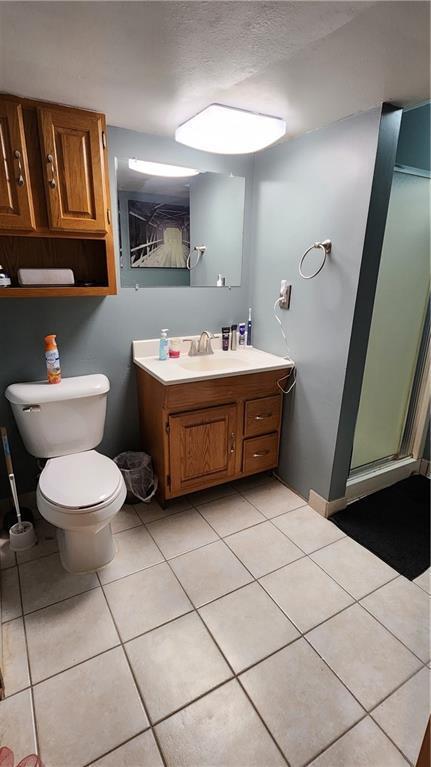 full bathroom featuring vanity, tile patterned floors, toilet, and a stall shower