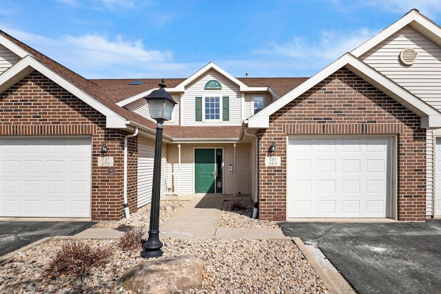 view of front of house featuring brick siding, driveway, a shingled roof, and a garage