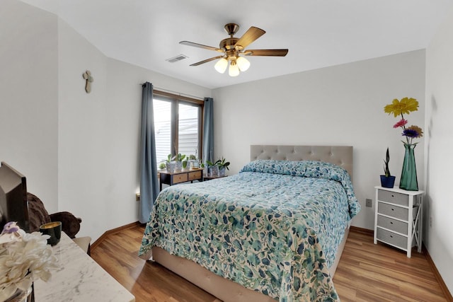 bedroom with ceiling fan, visible vents, baseboards, and light wood-style flooring