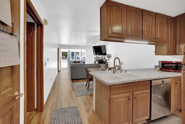 kitchen featuring light wood-type flooring, a sink, open floor plan, light countertops, and dishwasher