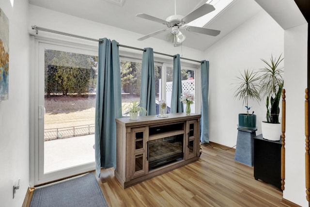 interior space with baseboards, a ceiling fan, lofted ceiling, and light wood-style floors