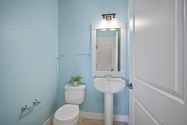 bathroom with tile patterned floors, baseboards, and toilet