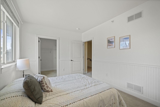 bedroom with visible vents, carpet, and a wainscoted wall