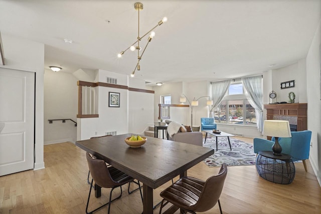 dining room with visible vents, a fireplace, light wood-style floors, and baseboards