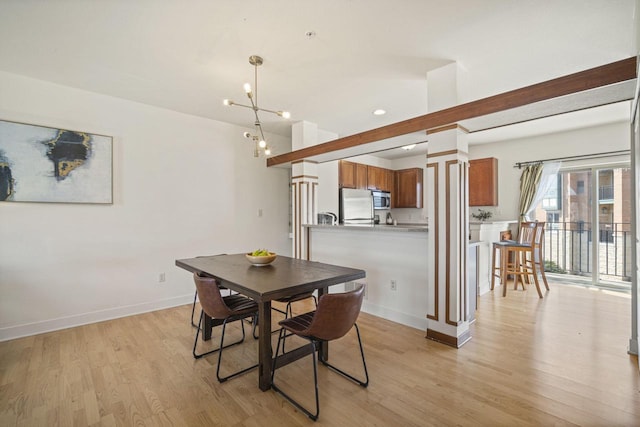 dining room with light wood finished floors, a chandelier, ornate columns, and baseboards