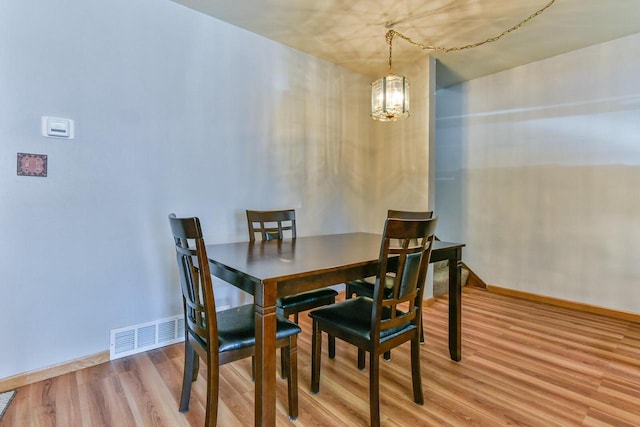 dining area featuring a notable chandelier, wood finished floors, visible vents, and baseboards