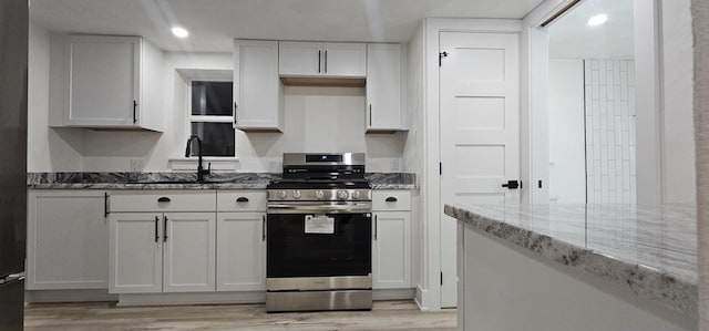 kitchen with light wood-type flooring, stone countertops, gas stove, recessed lighting, and white cabinets