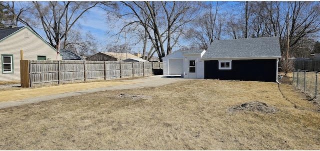 view of yard with an outdoor structure, fence, a garage, and driveway