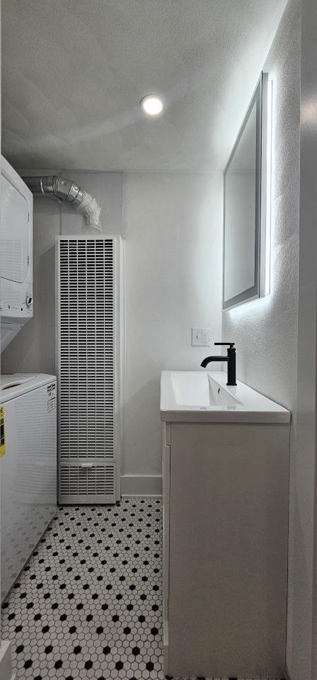 full bathroom featuring baseboards, vanity, a tile shower, tile patterned floors, and a textured ceiling